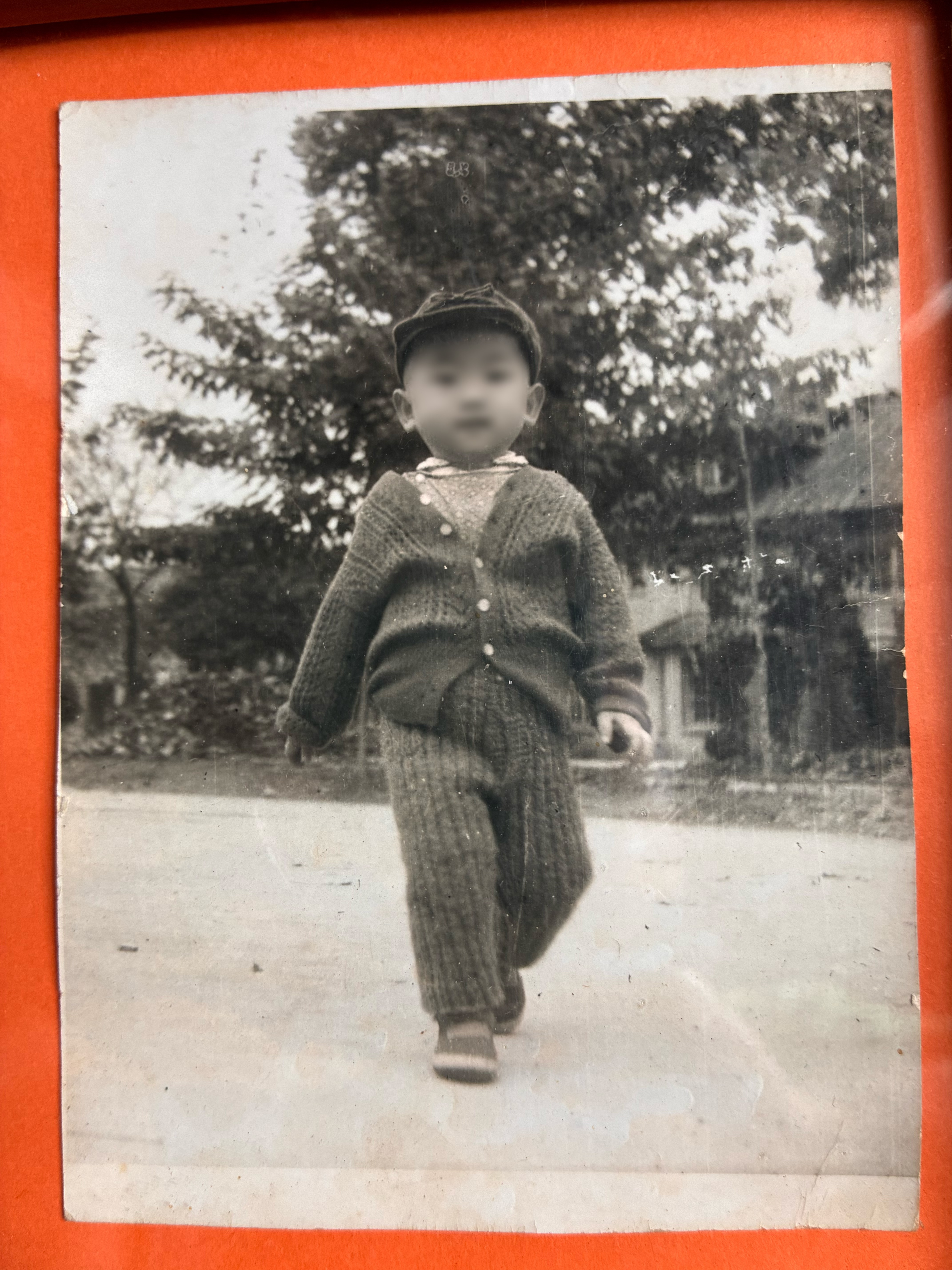 参与者提供的童年黑白照片:刚学会走路的孩子,保留红色相册边缘,面部已做隐私处理。