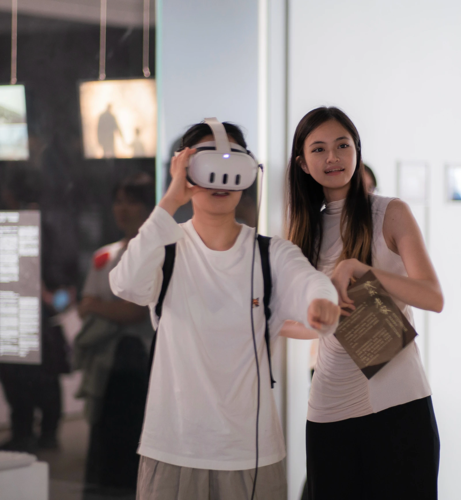 上海展览现场：一位观众佩戴 VR 头显体验作品，身旁有人陪同。