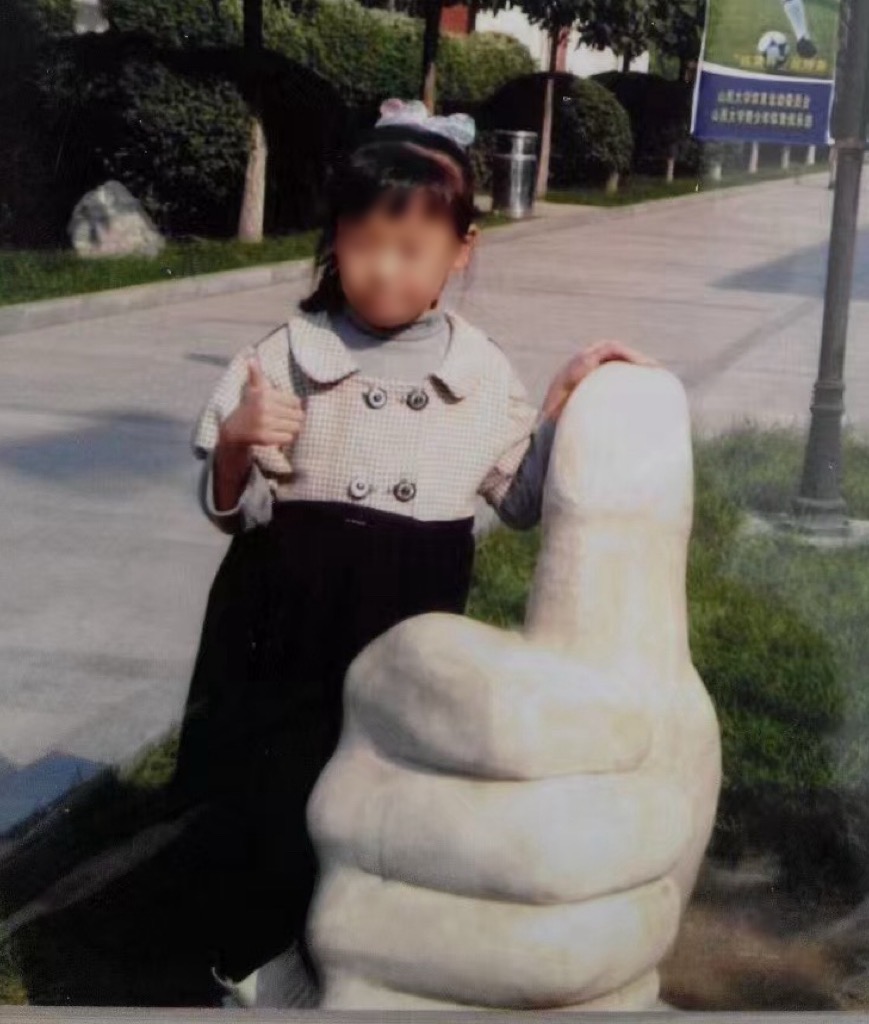 参与者约六岁时与大拇指雕塑的早期合影,人物面部已做隐私处理。